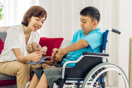 Téléchargez les photos : Portrait de jouir heureux amour famille asiatique mère jouer et soignant aider à regarder son enfant handicapé assis dans des moments de fauteuil roulant bon moment à la maison.concept de soins aux personnes handicapées - en image libre de droit