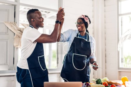 Téléchargez les photos : Portrait d'amour couple afro-américain s'amuser à cuisiner des aliments avec salade de légumes frais et ingrédients sandwich pour préparer le délicieux manger dans la cuisine à la maison - en image libre de droit