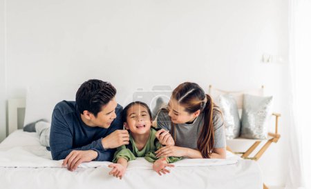 Téléchargez les photos : Portrait de jouir heureux amour asiatique famille père et mère tenant câlin mignon petite fille asiatique enfant souriant jouer et avoir des moments amusants bon temps à la maison - en image libre de droit