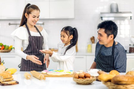 Téléchargez les photos : Portrait de jouir heureux amour asiatique famille père et mère avec petite fille asiatique enfant jouer et avoir plaisir à cuisiner des aliments avec biscuit de cuisson et ingrédient gâteau dans la cuisine - en image libre de droit