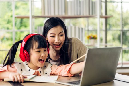 Téléchargez les photos : Mère et enfant asiatique petite fille apprendre et regarder ordinateur portable examen étude de leçon avec l'éducation en ligne e-learning.student chercher des connaissances éducatives dans l'école à la maison à la maison.Education - en image libre de droit