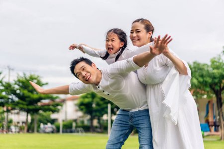 Téléchargez les photos : Portrait de jouir heureux amour asiatique famille père et mère tenant mignonne petite fille asiatique enfant souriant jouer et avoir des moments amusants bon temps dans le parc d'été à la maison - en image libre de droit