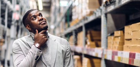 Téléchargez les photos : Portrait de souriant homme d'affaires afro-américain détails de la commande de vérifier les marchandises et les fournitures sur des étagères avec des marchandises fond dans warehouse.logistique et l'exportation d'affaires - en image libre de droit