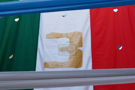 Foto de Bandera italiana con el número tres que indica el tercer campeonato SerieA ganado, durante los preparativos para la celebración de la victoria del campeonato de la Serie A italiana y el tercer escudo Scudetto "con los colores de la bandera italiana, que es w - Imagen libre de derechos