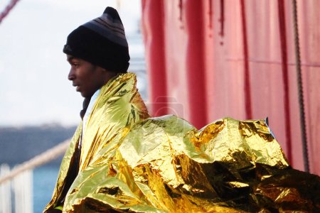 Foto de Migrante sale de la nave. El barco de rescate alemán "Sea-Eye 4" llega al puerto de Nápoles con 109 migrantes a bordo, incluidos 35 menores de edad, 18 mujeres, una de las cuales está embarazada y dos fallecidas.. - Imagen libre de derechos