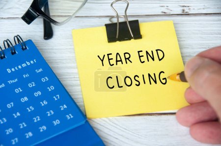 Photo for Year end closing written on yellow notepad with December calendar and glasses background. Year end closing and review concept. - Royalty Free Image