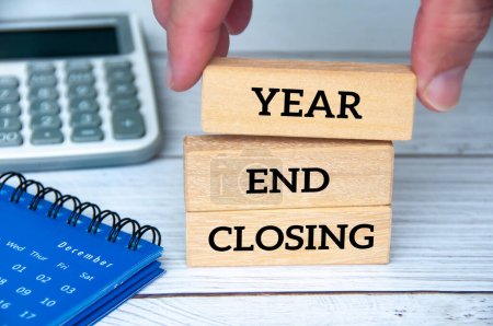 Texto de cierre de fin de año en bloques de madera con calendario de diciembre, gafas y bolígrafo. Concepto de cierre y revisión de fin de año.