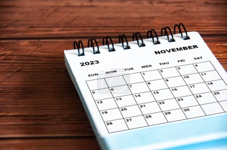 November 2023 weißer Schreibtischkalender auf hölzernem Tischhintergrund.