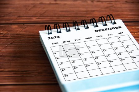 Dezember 2023 weißer Tischkalender auf hölzernem Tischhintergrund.