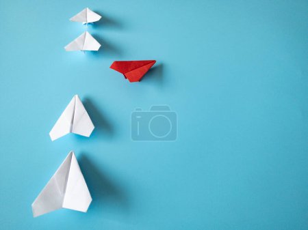 Téléchargez les photos : Red paper plane origami leaving other white planes on blue background. Leadership skills concept. - en image libre de droit