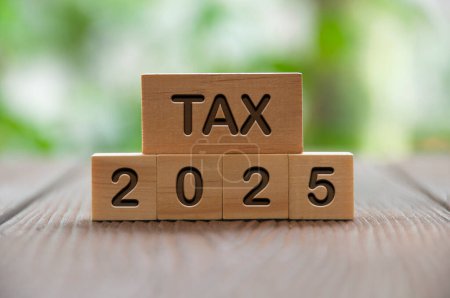 Foto de Tax 2025 text on wooded blocks with blurred nature background. Taxation concept. - Imagen libre de derechos