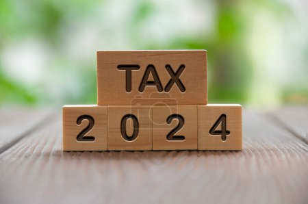 Téléchargez les photos : Tax 2024 text on wooded blocks with blurred nature background. Taxation concept. - en image libre de droit
