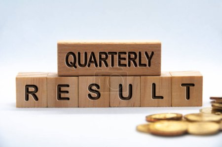 Quarterly result text engraved on wooden blocks with golden coins background. Business result concept.