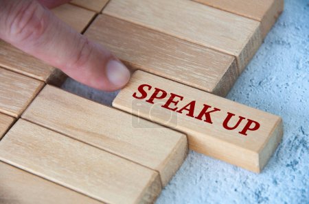 Finger pushing wooden block with written text speak up. Courage and speak up concept.