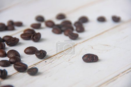 Téléchargez les photos : Grains de café dispersés sur fond de couverture en bois avec un espace personnalisable pour des idées de texte ou de café. - en image libre de droit