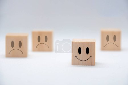 Rostros felices y tristes de emoción en cubos de madera. Concepto de satisfacción y evaluación del cliente