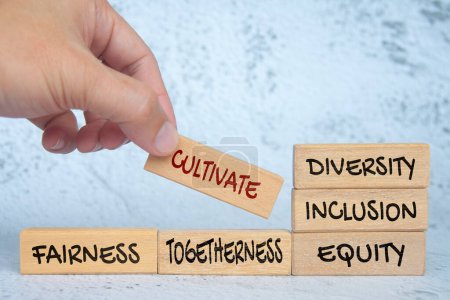 Holzklötze mit Text von Hand platzieren - Vielfalt, Inklusion, Gerechtigkeit pflegen. Miteinander und Fairness. Konzept der Vielfalt respektieren.
