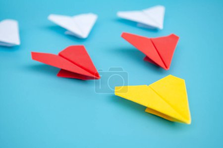 Téléchargez les photos : Origami avion en papier jaune menant d'autres avions en papier sur fond bleu. Concept de leadership. - en image libre de droit