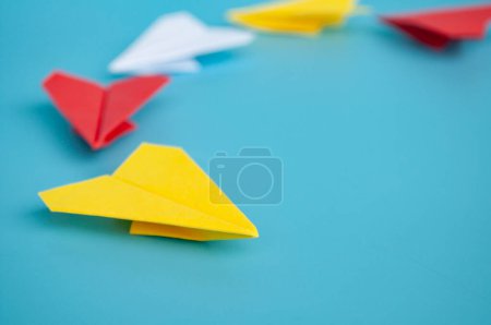 Téléchargez les photos : Origami avion en papier jaune menant d'autres avions en papier sur fond bleu. Concept d'espace de leadership et de copie. - en image libre de droit