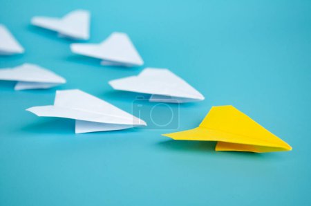 Téléchargez les photos : Origami avion en papier jaune menant d'autres avions en papier blanc sur fond bleu. Concept de leadership. - en image libre de droit