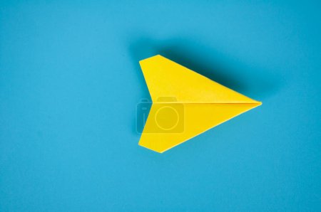 Téléchargez les photos : Vue du dessus de l'avion en papier jaune sur fond bleu. Espace pour le texte ou les idées. Espace de copie. - en image libre de droit