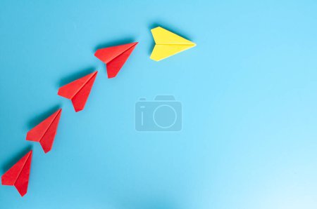 Téléchargez les photos : Vue du dessus de l'origami de l'avion en papier jaune menant avions en papier rouge sur fond de couverture bleue. - en image libre de droit