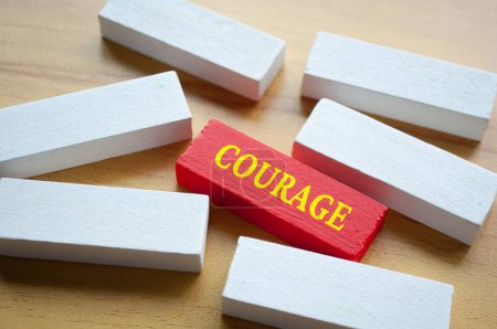 Courage text on red wooden block surrounded by white wooden blocks. Courage culture concept.