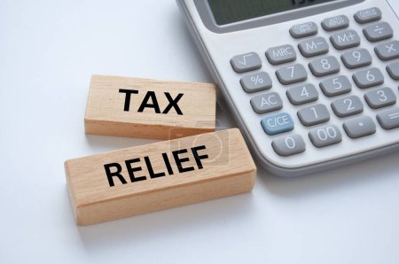 Steuererleichterungstext auf Holzblöcken auf weißem Einband-Hintergrund mit Taschenrechner-Hintergrund. Steuerkonzept.