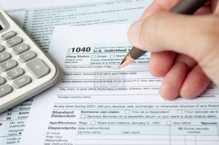 Ausfüllen des Steuerformulars mit Steuerformular und Taschenrechner-Hintergrund. Steuer- und Selbstbewertungskonzept.