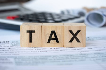 Steuerwort auf Holzwürfeln mit Steuerformular und Taschenrechner-Hintergrund. Steuerkonzept.
