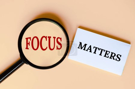 Top view of magnifying glass and notepad with text, Focus matters.
