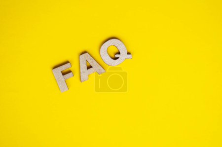 Foto de Vista superior del texto FAQ de madera sobre fondo amarillo. Preguntas frecuentes concepto. - Imagen libre de derechos