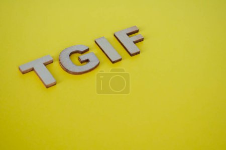 TGIF letras de madera que representan Gracias a Dios Es Viernes sobre fondo amarillo.