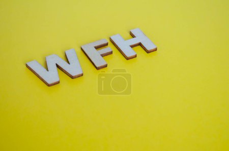 Letras de madera WFH que representan Work From Home sobre fondo amarillo.
