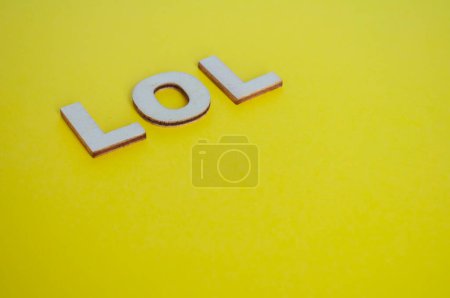 LOL Holzbuchstaben, die lautes Lachen auf gelbem Hintergrund darstellen.