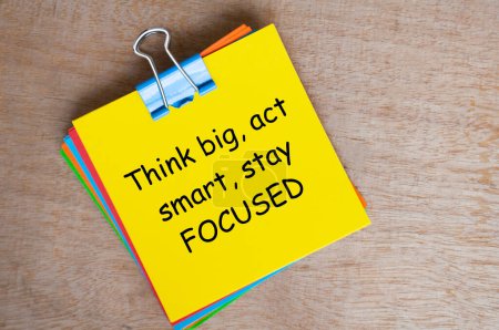 Think big, act smart, stay focused text on yellow notepad.