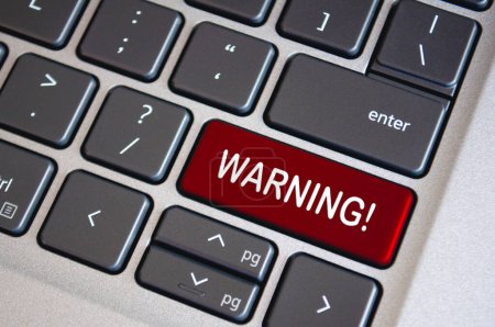 Warning text on dark red laptop keyboard. Security and warning concept.