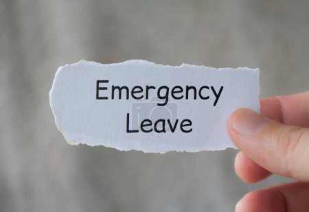Hand hält zerrissenes Papier mit Emergency Leave Text mit unscharfem Hintergrund.