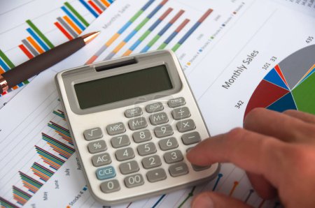 Calculatrice manuelle avec papier d'analyse financière. Stratégie d'entreprise et concept budgétaire.