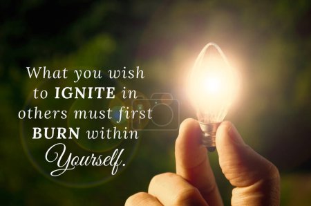 What you wish to ignite in others must first burn within yourself quote with hand holding shining bulb background. Inspirational quotes concept.