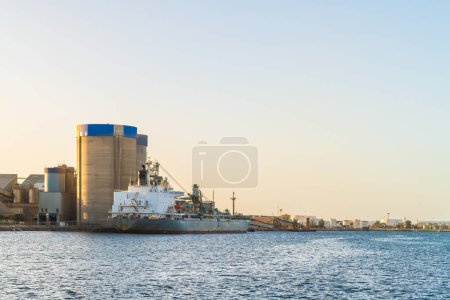Photo for Commercial cement carrier at Port Adelaide docks viewed across the Port River at sunset, South Australia - Royalty Free Image