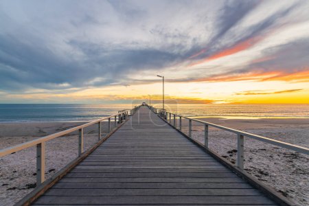 Téléchargez les photos : Henley Beach jetée au coucher du soleil avec la mer tranquille et les nuages au-dessus, Australie du Sud - en image libre de droit