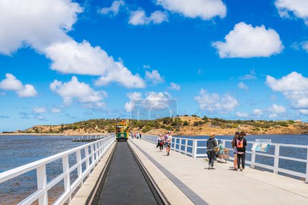 Téléchargez les photos : Victor Harbor, Australie du Sud - 5 janvier 2022 : Les gens marchent le long de la nouvelle causway Granite Island, tandis que le tramway Horse Drawn passe par un jour lumineux - en image libre de droit