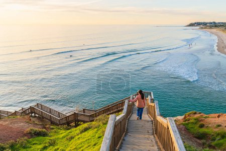 Anmutig steigt eine Frau die Treppe zum South Port Beach hinunter, fasziniert vom spektakulären Meerblick während des Sonnenuntergangs, Port Noarlunga, Südaustralien