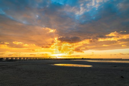 Moonta Bay beach with people walking on the jetty against dramatic sunset, South Australia
