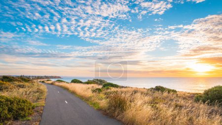 O 'Sullivan Beach Radweg entlang der Küste mit Wolken über dem Meer bei Sonnenuntergang, Südaustralien
