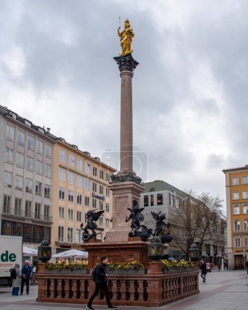 Foto de Estatua dorada de María encima de Mariensaule situada en la Marienplatz en Munich, Alemania. - Imagen libre de derechos