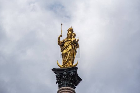 Foto de Estatua dorada de María encima de Mariensaule situada en la Marienplatz en Munich, Alemania. - Imagen libre de derechos