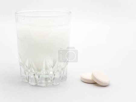 Téléchargez les photos : Pilules et verre d'eau avec des pilules dissolvantes sur blanc - en image libre de droit