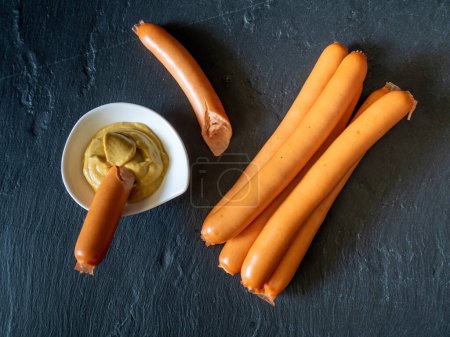 Photo for Boiled sausages served with mustard on black slate - Royalty Free Image